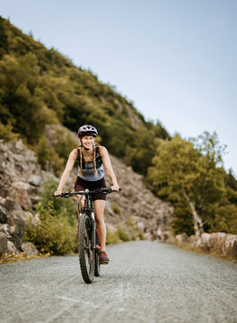 Young woman rides bike along dirt road in Acadia National Park, Maine