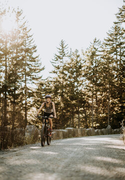 Woman cycles along dirt path in Acadia National Park, Maine