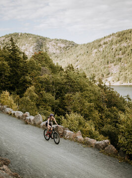 woman rides mountain bike along gravel path, Acadia National Park