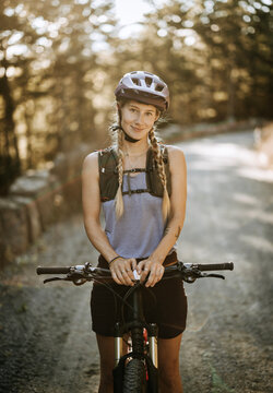 Beautiful female mountain biker smiles while posing for portrait.