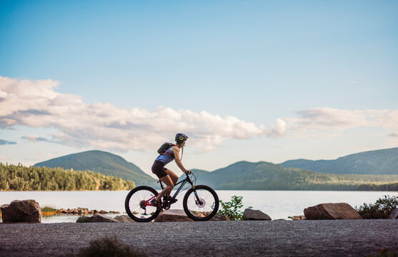 Cyclist rides bike on carriage trail past Eagle Lake, Acadia Park