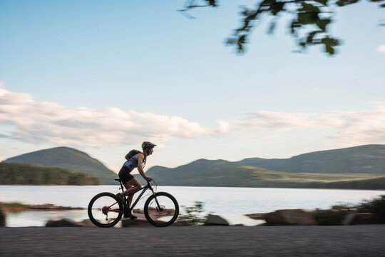 Speedy cyclist rides fast past lake in Acadia National park