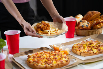 Women's hands holding breakfast, croissants, bakery, pizza on the table, preparing a party.