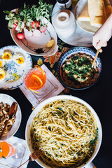 high angle view of table full of food and drink: eggs, pasta, mushrooms, beans, radishes, spring meal, cocktail