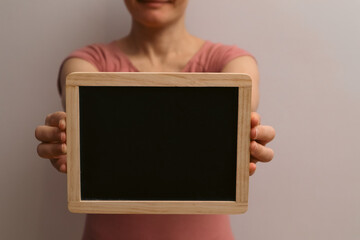 Holding Blank Blackboard. Woman showing chalkboard. Cropped image of woman holding empty black board