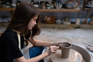 Young women is making earthenware at workshop.