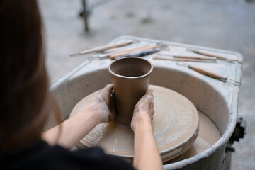 Young women is making earthenware at workshop.