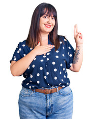 Young plus size woman wearing casual clothes smiling swearing with hand on chest and fingers up,...