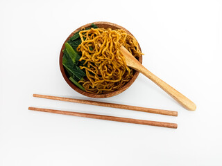 A serving of spicy fried noodles with vegetables and tofu, beautifully presented in a wooden bowl...