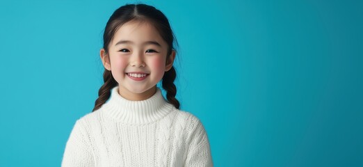 Smiling girl with braided hair wearing cozy white sweater against bright blue background, copy space for text