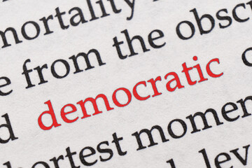 Fototapeta premium Focus on the red word Democratic. Macro shot printed red colour word Democratic on a piece of paper or book