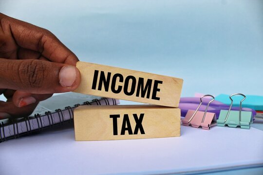 Income tax symbol. Concept words 'income tax' on wooden blocks on a beautiful white backgrounds. Businessman hand. Business, income tax concept.