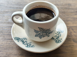 Coffee in a white cup on a wooden table.	