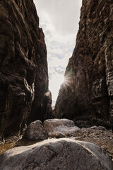 View from within a narrow gorge in Iran, looking out towards the sunny sky. Large boulders and towering rock walls create a dramatic landscape. Photographed on November 12, 2024.