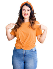 Beautiful young brunette woman wearing casual clothes looking confident with smile on face,...