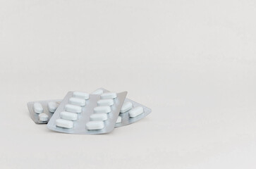Three blister packs of tablets on light background, close-up. Pharmaceutical industry concept