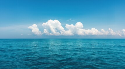 Obraz premium Serene ocean view with fluffy clouds and clear blue sky
