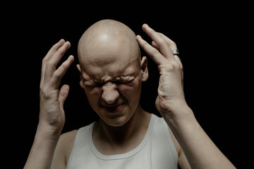 Portrait of bald man with screwed up face experiencing sudden intense headache raising arms in...