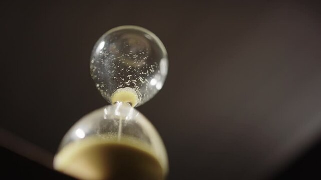 Last sand particles falling through bottleneck of hourglass, deadline concept
