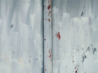 Silver roughly painted metal door with hints of red