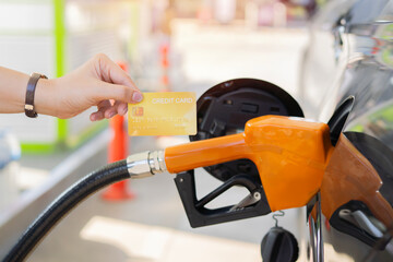 Fototapeta premium Woman paying credit card after refuel car ​spending at gas station.