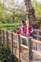 Two women walking with bicycle enjoying nature in countryside