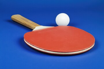 A table tennis setup featuring a red racket and a ball against a blue backdrop