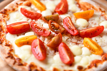 Pizza with mozzarella cheese and cherry tomatoes on wooden background. Soft focus. Close up.