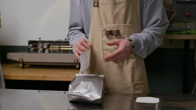 Cropped shot of unrecognizable production factory colleagues in uniform putting labels on coffee bags