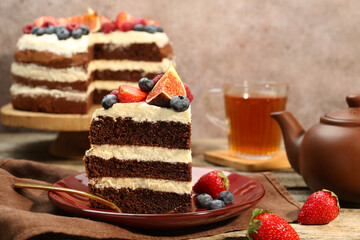 Piece of delicious chocolate sponge cake with berries served on wooden table