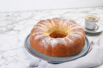 Freshly baked sponge cake and coffee on white marble table