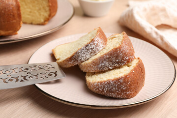 Pieces of freshly baked sponge cake and server on wooden table, closeup