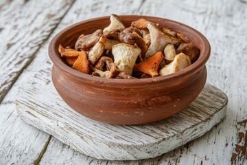 Fototapeta premium Detailed view of a brown ceramic bowl filled with cooked assorted mushrooms on a white rustic wooden surface