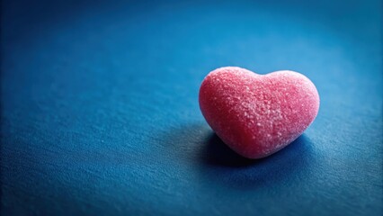 A single Lovehearts candy perched on a deep blue background with subtle texture, showcasing its rounded shape and bright pink color against the darker hue , love hearts, candies