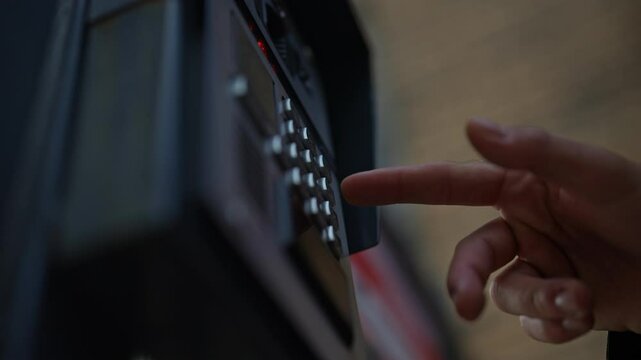 Low-angle view of finger pressing button on intercom keypad, located on building exterior, allowing access to resident or employee. Concept of modern technology connecting visitors to secure entrances