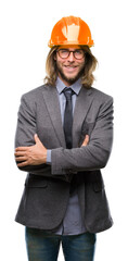 Young handsome architec man with long hair wearing safety helmet over isolated background happy face smiling with crossed arms looking at the camera. Positive person.