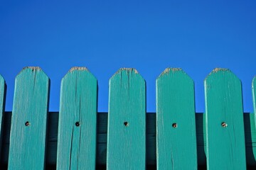Green Palisade fence set against a vibrant blue sky