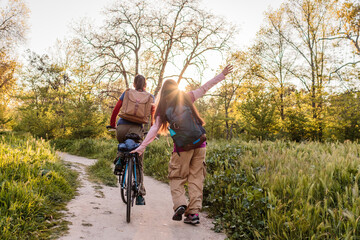 Happy women walking and cycling in nature at sunset