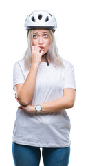 Young blonde woman wearing cyclist security helmet over isolated background looking stressed and nervous with hands on mouth biting nails. Anxiety problem.