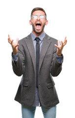 Young handsome business man over isolated background crazy and mad shouting and yelling with aggressive expression and arms raised. Frustration concept.