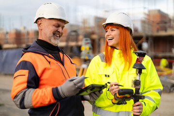 Construction workers manager and surveyor collaborating on site using digital tools and equipment...