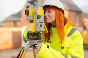 Female Surveyor focuses on measuring equipment at a construction site during the day