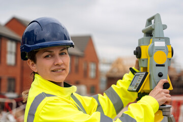 Pretty Female Construction worker using surveying equipment on a building site in a residential area during daylight