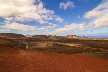 Beautiful red sandy plains in the middle of the desert with blue sky and clouds