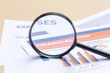 Close-up of a magnifying glass highlighting financial trends on a graph sheet.