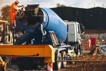 Construction workers operating a blue cement mixer at a construction site during daylight hours