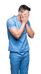 Handsome young doctor surgeon man over isolated background with sad expression covering face with...