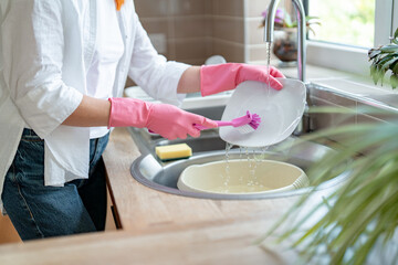 Washing dishes in a modern kitchen while wearing gloves to prevent water exposure