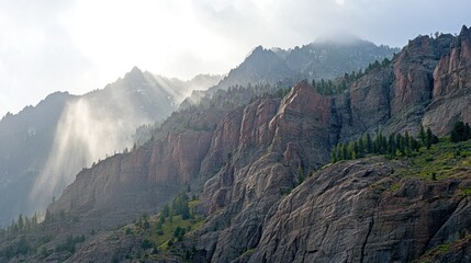 Obraz premium Majestic Mountain Panorama: Sunbeams Piercing Through Misty Peaks