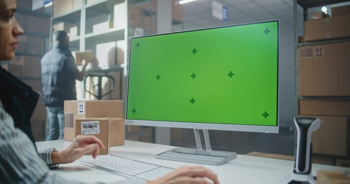 Warehouse Retail Center: Female Inventory Manager Works on PC, Checks Delivery Information of Parcels with E-Commerce Online Orders, Goods. Computer Screen with Green Screen Template. Dolly Shot.